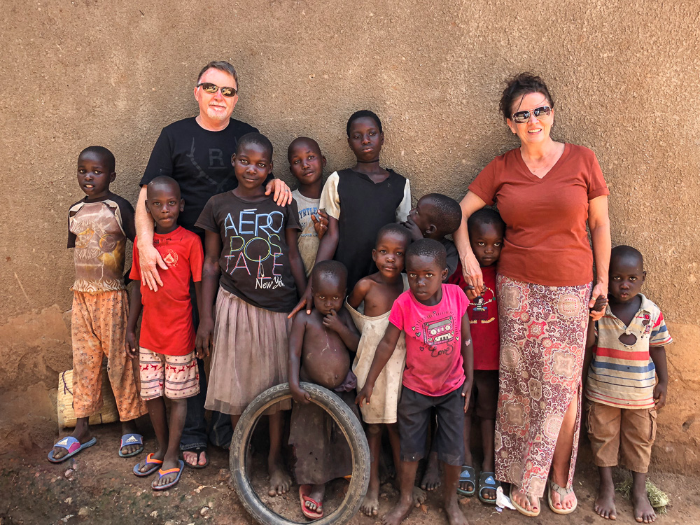 Russ & Rhonda Rhoden stand with a group of Uganda children against a concrete wall